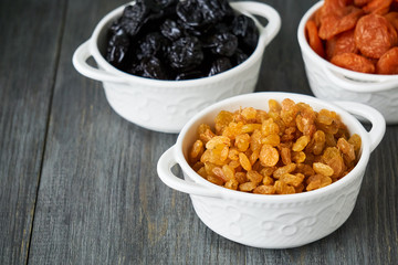 Various dried fruits in white bowls on wooden background