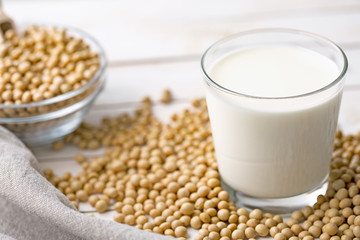 Raw soy seeds and glass of milk on slate background. Organic farming
