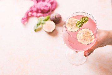 Pink cocktail with fig and basil on light background close up