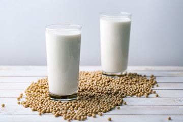 Raw soy seeds and glass of milk on slate background. Organic farming