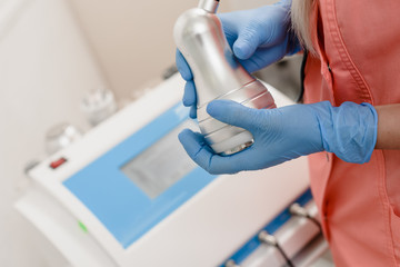 Closeup of cosmetologist's hand pressing button on modern laser machine