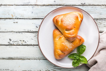 Homemade chicken and mushroom mini pies on plate over white wooden background, top view