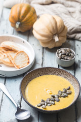 Seasonal autumn food. Healthy Pumpkin soup with cream and organic pumpkin seeds.