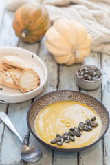 Seasonal autumn food. Healthy Pumpkin soup with cream and organic pumpkin seeds.