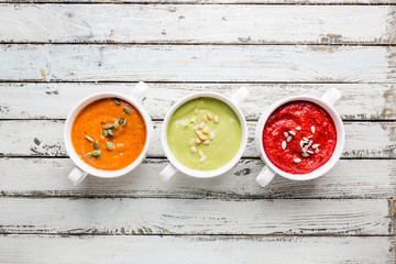 Variety of different colorful vegetable cream soups in a bowls, top view. Concept of healthy eating or vegetarian food.