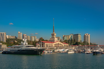 Obraz premium Sea port in summer. Many different yachts and boats stand at the marina. Yachtsmen and travelers are preparing to sail in the sea. In the background of the building of the seaside city.