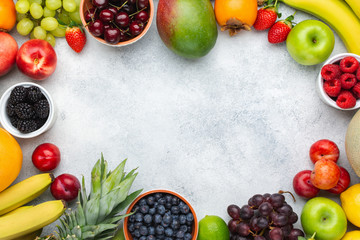 Healthy fruit background frame, strawberries raspberries oranges plums apples kiwis grapes blueberries mango persimmon on the white table, above view, copy space for text, selective focus