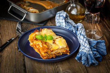 Piece of tasty hot lasagna with red wine.