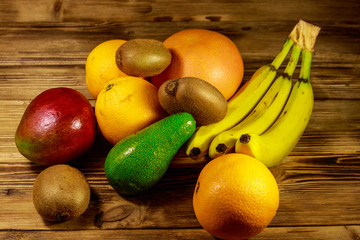 Assortment of tropical fruits on wooden table. Still life with bananas, mango, oranges, avocado, grapefruit and kiwi fruits