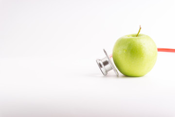 Green Apple with medical stethoscope isolated on white background for healthy eating. Selective focus and crop fragment. Healthy and copy space concept