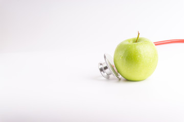Green Apple with medical stethoscope isolated on white background for healthy eating. Selective focus and crop fragment. Healthy and copy space concept