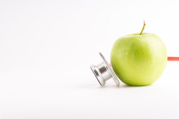 Green Apple with medical stethoscope isolated on white background for healthy eating. Selective focus and crop fragment. Healthy and copy space concept
