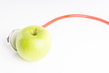 Green Apple with medical stethoscope isolated on white background for healthy eating. Selective focus and crop fragment. Healthy and copy space concept