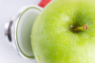 Green Apple with medical stethoscope isolated on white background for healthy eating. Selective focus and crop fragment. Healthy and copy space concept