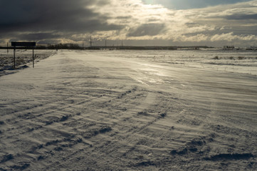 Desolate empty, icy road and harsh sunlight