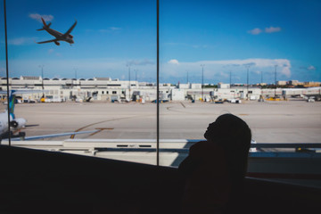 little girl waiting in airport, looking at planes, family travel
