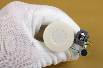 A technician controls the quality of a mini speaker an microphone  for phone handset