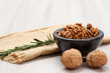 Walnuts in stone bowl with rosemary on a wooden boards.