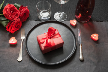 Valentine's day or birthday dinner. Elegance table setting with red rose on black linen tablecloth.