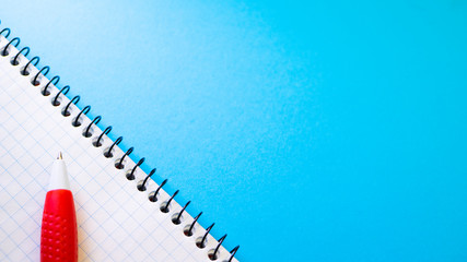 Notepad for entries with pen on blue background. View from above with copy space