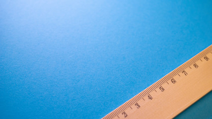 Wooden ruler on blue background. View from above with copy space