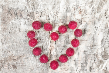 Raspberies in form of heart wooden background