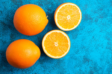 Orange halves and whole ripe citrus fruits on a blue background, top view