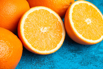 Orange halves and whole ripe citrus fruits on a blue background
