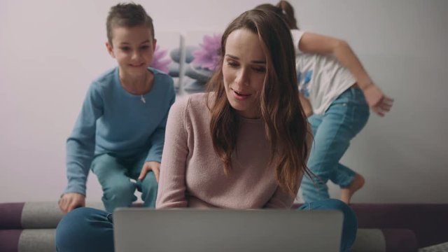 Mother with children waving hand on video call online at laptop