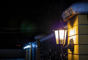 Old style street lamp with falling snow at night