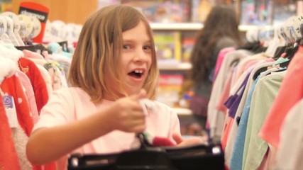 Happy 8 year old girl shopping for clothes in fashion store. Slow moton, 4K UHD.