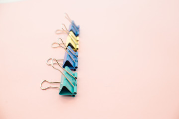 colored paper clips on a pink background. Office stationary