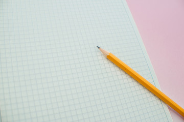A pencil on a notebook in the linel. School supplies. White sketch book with orange pencil. Note book and pencil