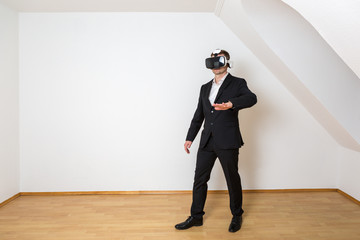 Geschäftsmann geht mit seiner Hand die virtuelle Einrichtung im leeren, weißen Raum ab