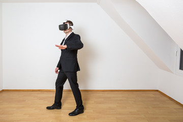 Geschäftsmann geht mit seiner Hand die virtuelle Einrichtung im leeren, weißen Raum ab