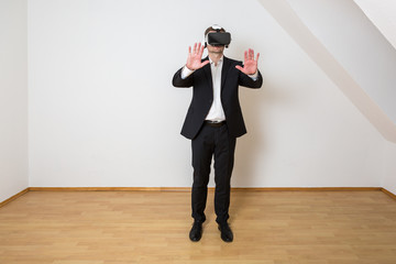 Mann bewegt sich im leeren, weißen Raum mit Laminat Boden und betrachtet die virtuelle Einrichtung...