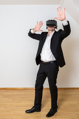 Mann mit VR Brille bewegt sich dynamisch im leeren Raum. Er testet seine virtuelle Einrichtung.