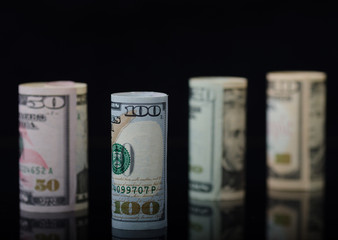 Dollar banknotes rolls on black background with reflection. Business concept.