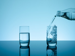Creative splashing water in the glass on blue background.