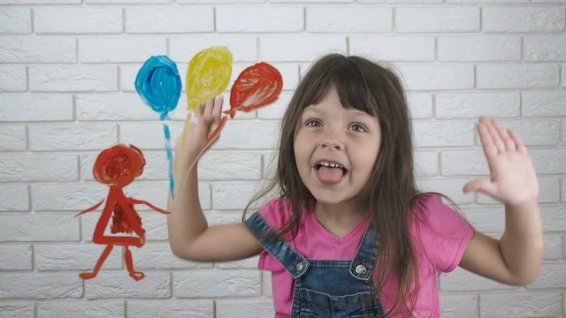 Child shows tongue. Happy little girl with her drawing shows her tongue.