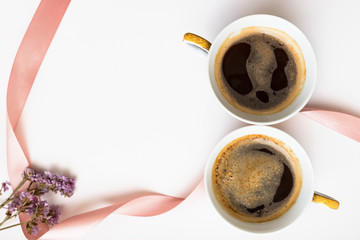 Two cups of coffee in the form of a figure 8. Pink ribbon with flowers. Flat lay, top view. Valentines and 8 March Mother Womens Day concept