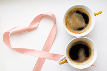 Two cups of coffee in the form of a figure 8. Pink ribbon heart. Flat lay, top view. Valentines and 8 March Mother Womens Day concept