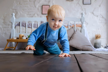 Naklejka premium Beautiful blue-eyed baby crawling on the wooden floor