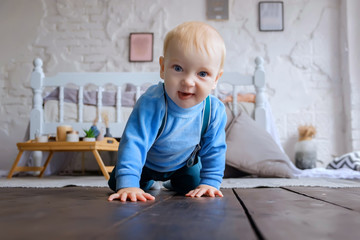Naklejka premium Beautiful blue-eyed baby crawling on the wooden floor