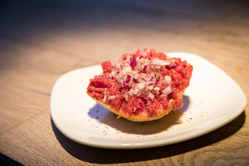 Teller Beef Tatar Mettbrötchen mit Rindfleisch und Zwiebeln auf Holz Tisch