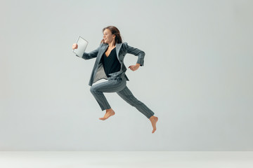 Happy business woman dancing and smiling in motion isolated over white studio background. Human...