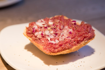 Teller Beef Tatar Mettbrötchen mit Rindfleisch und Zwiebeln auf Holz Tisch