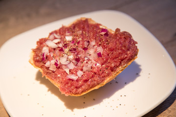 Teller Beef Tatar Mettbrötchen mit Rindfleisch und Zwiebeln auf Holz Tisch