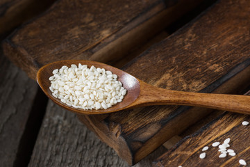 Sesame seeds in a wooden spoon on a wooden table. Organic food for health. Rustic style