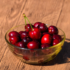 Berries of a sweet cherry in a glass bowl on a wooden background